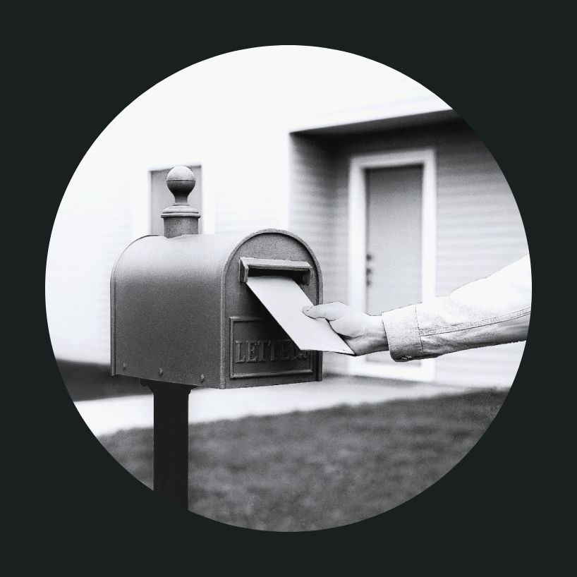 Hand placing mail into a mail box.