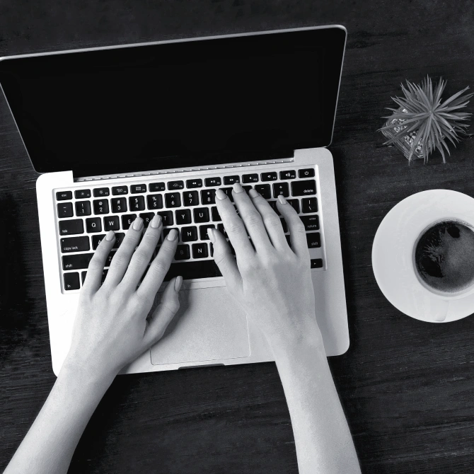 Aerial view of female hands typing on a laptop, working on digital marketing and analytics.
