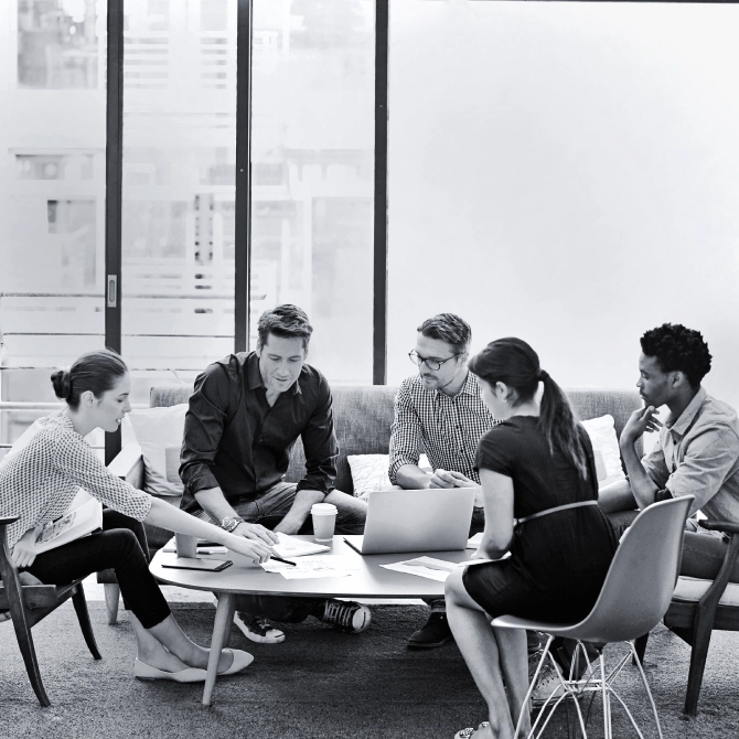 Small group of business men and women sitting around a table, discussing digital marketing.